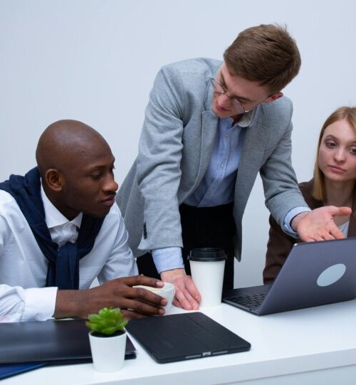 A white male, black male and white female looking into a laptop