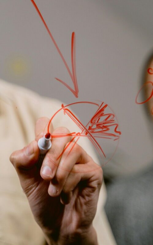 Man writing on board watched by female